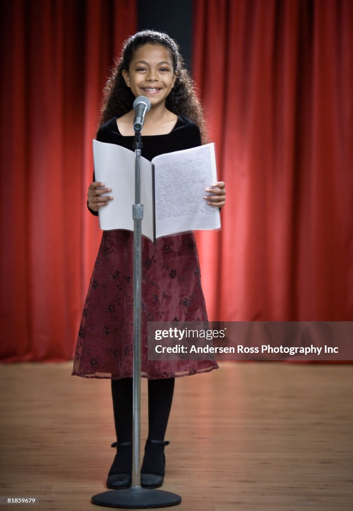 Mixed Race girl reading on stage
