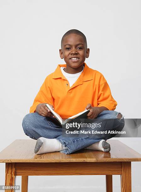 african boy holding book - boy sitting stock pictures, royalty-free photos & images