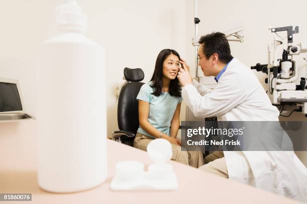 asian male optometrist examining patient - contact lens case stock pictures, royalty-free photos & images