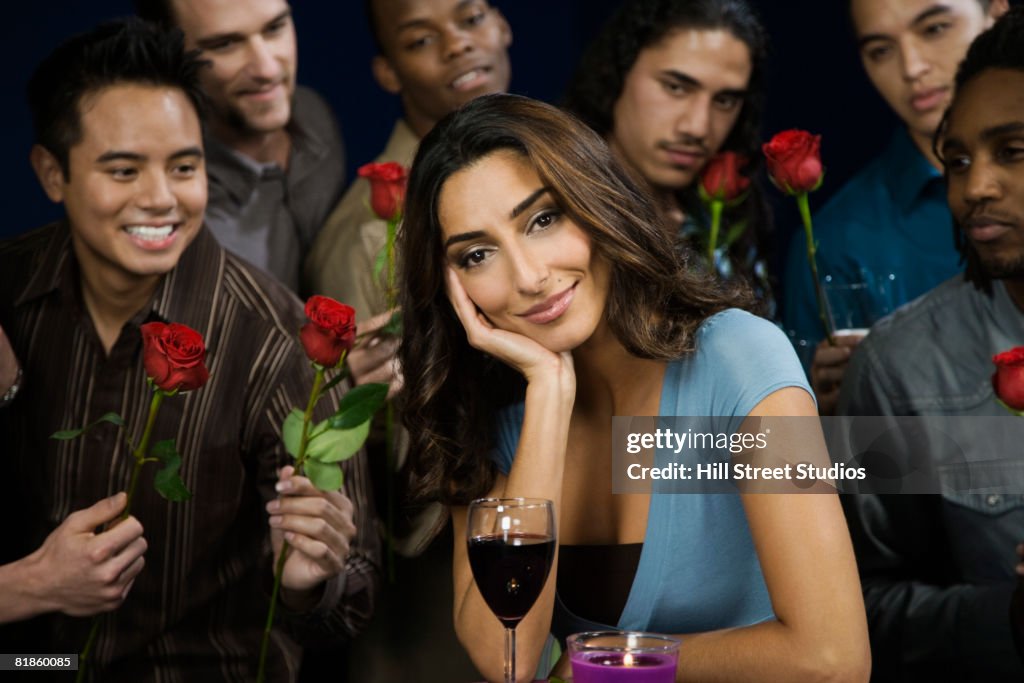 Multi-ethnic men giving roses to woman