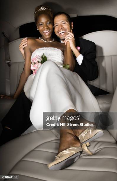 multi-ethnic newlyweds in back of limousine - bride and groom wedding car stock pictures, royalty-free photos & images