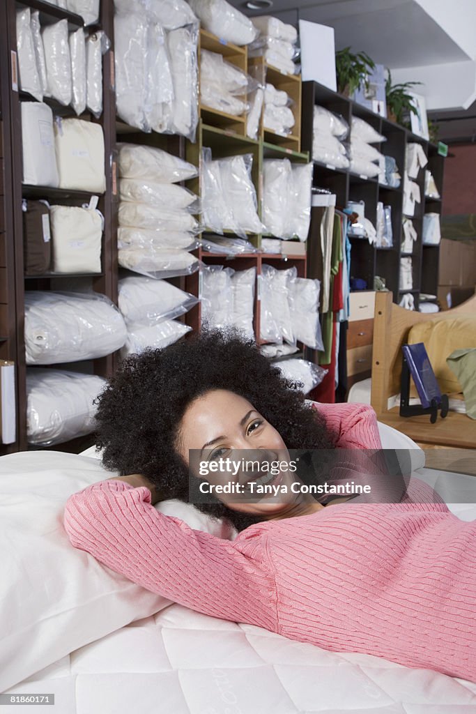African woman laying on bed in store