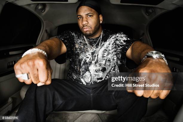 african man holding out fists in limousine - rich fury stockfoto's en -beelden