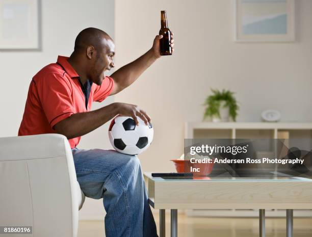 african man holding soccer ball and cheering - african soccer fans photos et images de collection