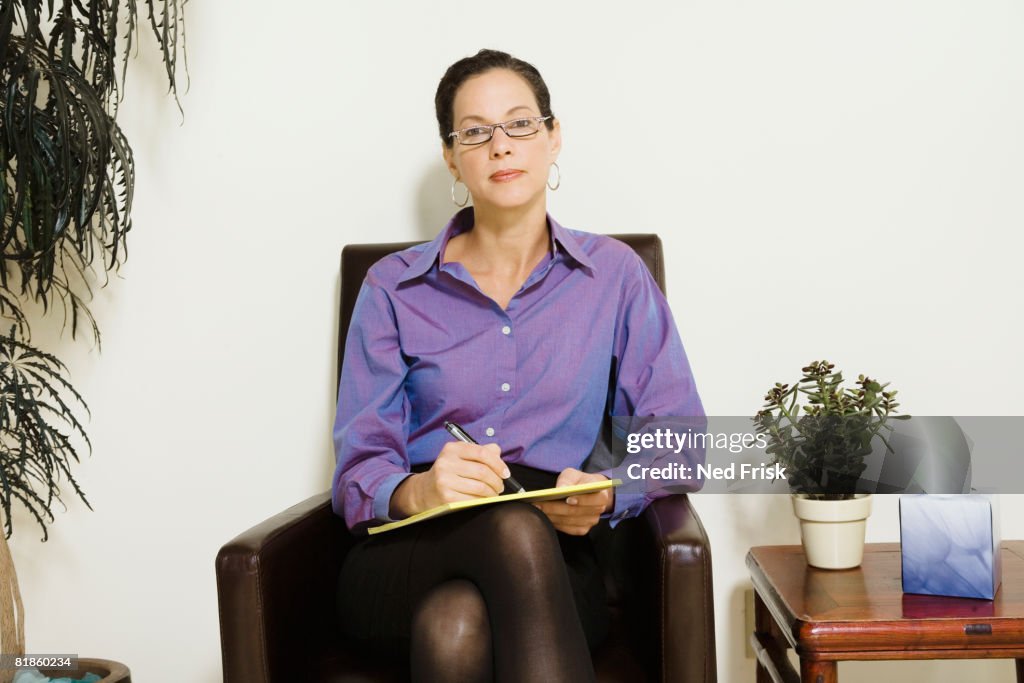Mixed Race female psychiatrist holding notepad