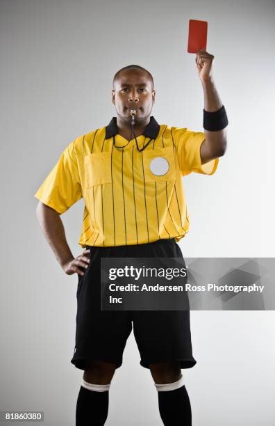 african male referee holding red card - referee stockfoto's en -beelden