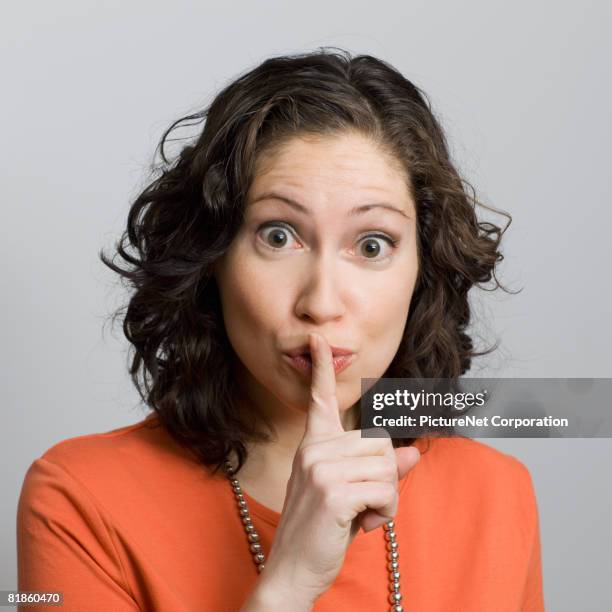 hispanic woman shushing - finger on lips stock pictures, royalty-free photos & images