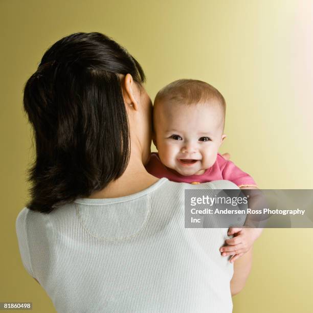asian baby looking over mother?s shoulder - mom holding baby stock-fotos und bilder