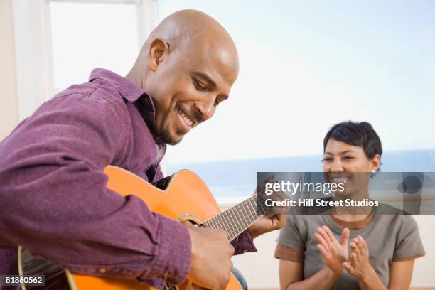 african man playing guitar for wife - cantare una serenata foto e immagini stock