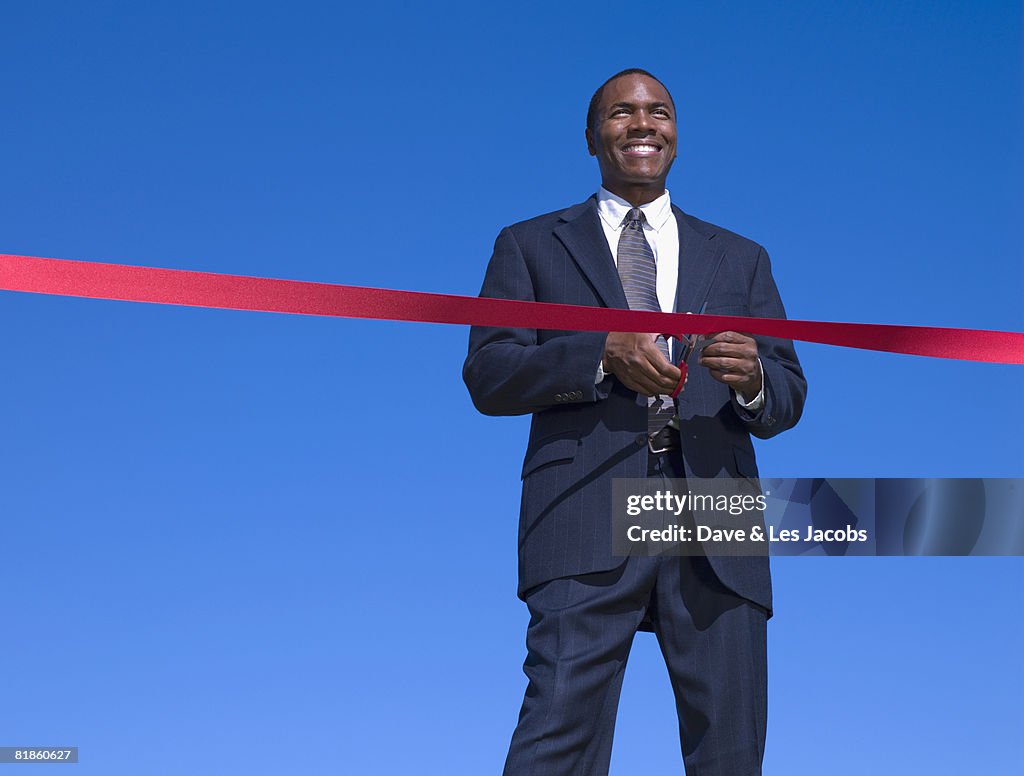 African businessman cutting ribbon