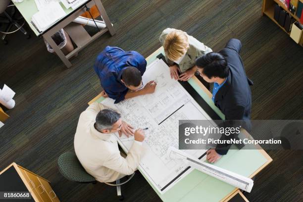 multi-ethnic architects looking at blueprints - architectural designer stock pictures, royalty-free photos & images