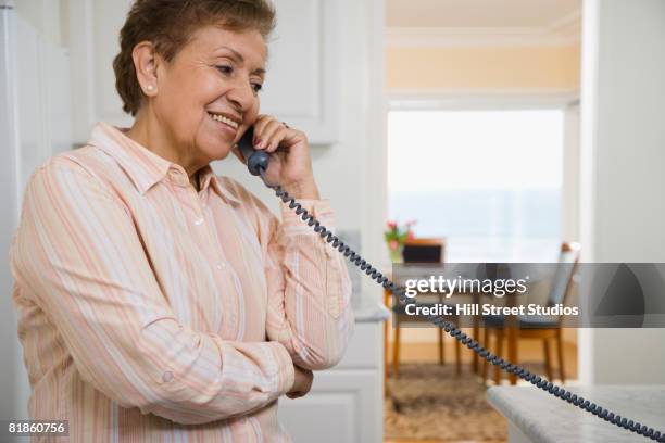 senior hispanic woman talking on telephone - teléfono con cable fotografías e imágenes de stock