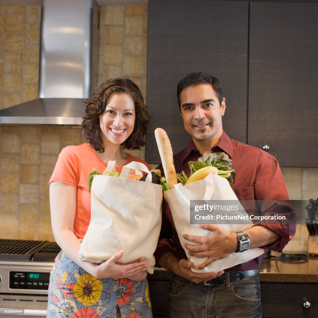 Hispanic couple holding grocery bags