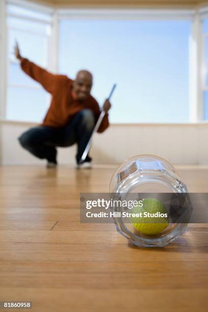 african man practicing golf at home - putting indoors stock pictures, royalty-free photos & images