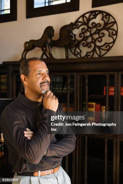 african man thinking with hand on chin - man looking up beard chin stock-fotos und bilder