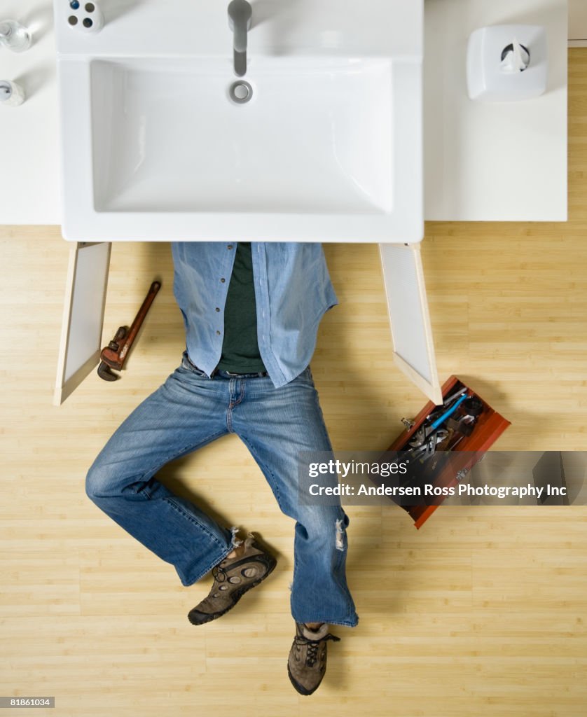 Native American man repairing bathroom sink