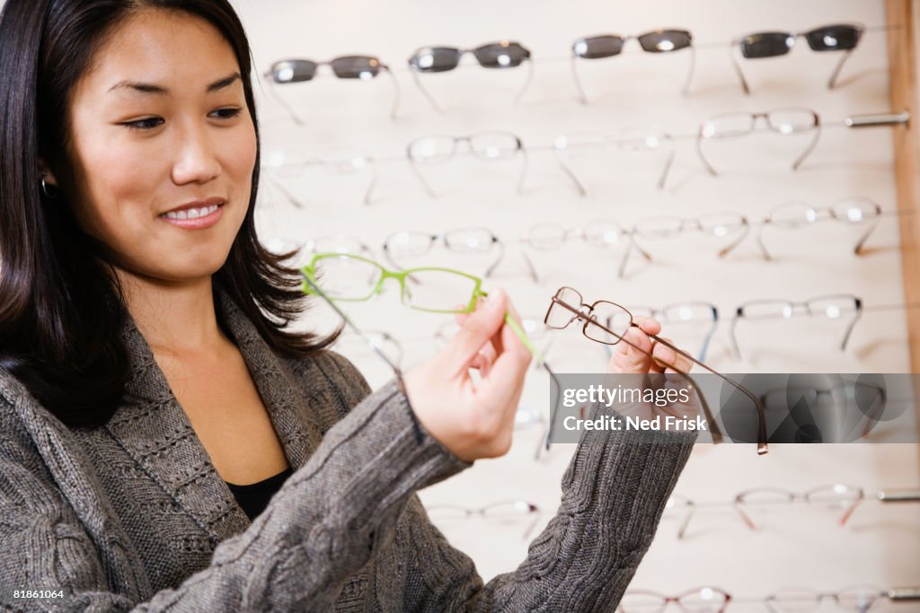 Asian woman comparing eyeglasses