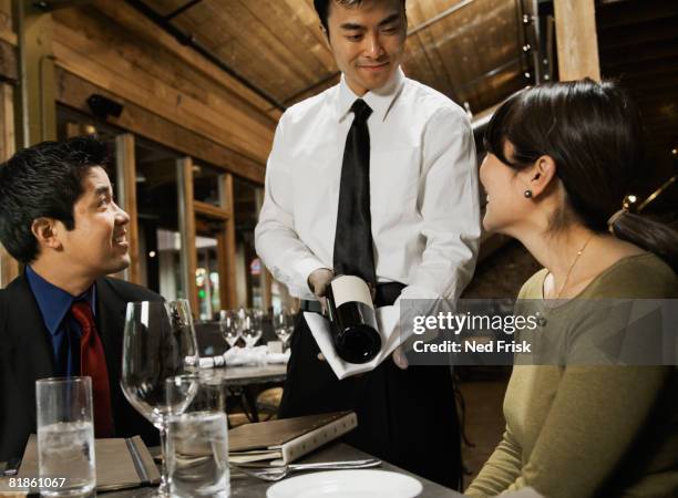 asian waiter showing wine to couple - sommelier stock-fotos und bilder