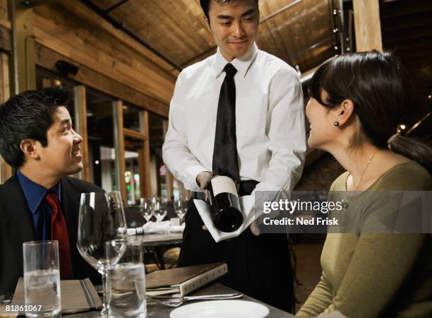 asian waiter showing wine to couple - sommelier stock pictures, royalty-free photos & images