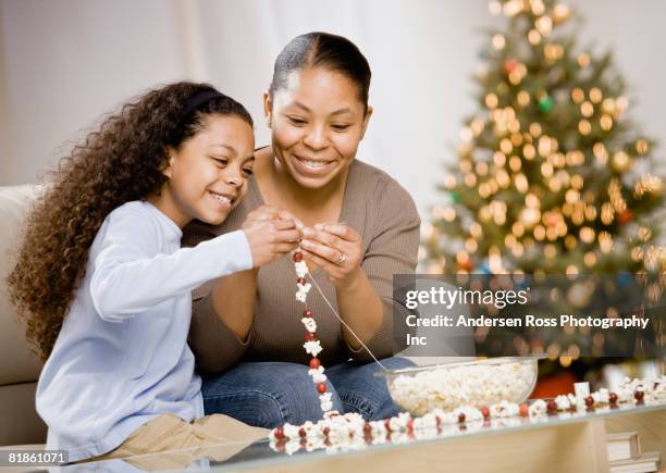 mixed race mother and daughter stringing popcorn garland - resourceful bildbanksfoton och bilder