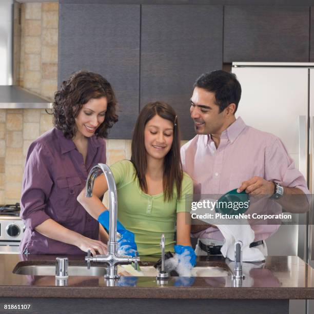 hispanic family washing dishes - kids with cleaning rubber gloves stock-fotos und bilder