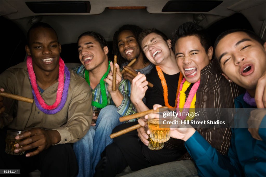 Multi-ethnic men celebrating in limousine