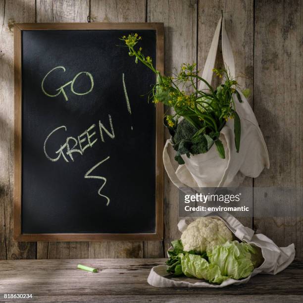 green leafy vegetables in natural cotton reusable bags next to a wooden framed blank blackboard with 'go green!' written in green chalk on it. - chalk wall stock pictures, royalty-free photos & images