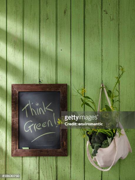 verduras de hojas verdes en una bolsa reutilizable de algodón natural junto a una pizarra en blanco enmarcada de madera con 'go green!' escrita en tiza verde. - chalk bag fotografías e imágenes de stock
