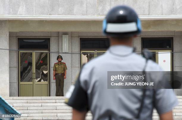 North Korean soldier looks at the south side as a South Korean soldier stands guard during a press tour to the truce village of Panmunjom in the...