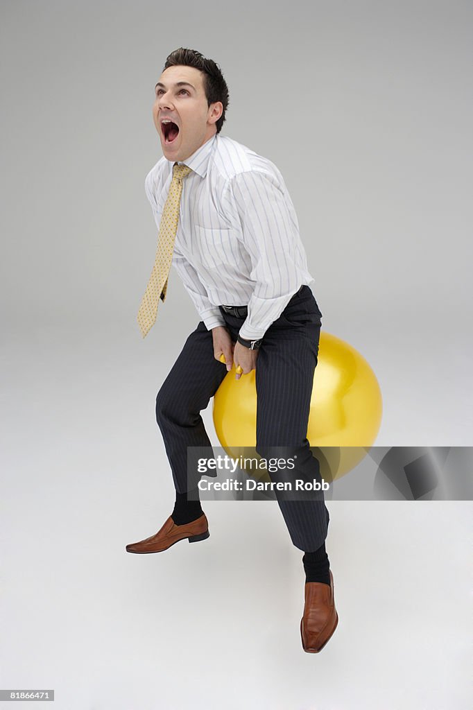 Businessman riding on a space hopper, screaming