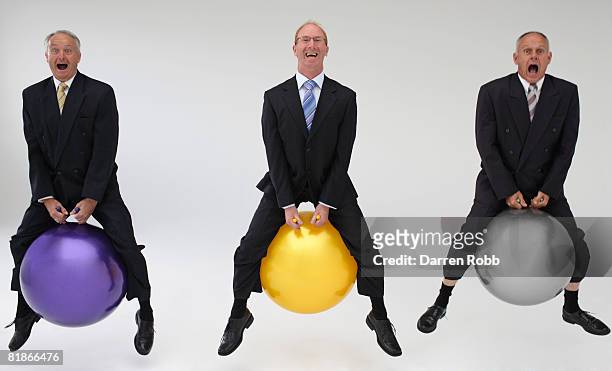 three mature businessmen bouncing on space hoppers, laughing - business man laughing stock-fotos und bilder