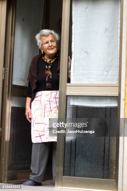 scicli, sicília: mulher sênior com avental fica na porta - mezzogiorno - fotografias e filmes do acervo