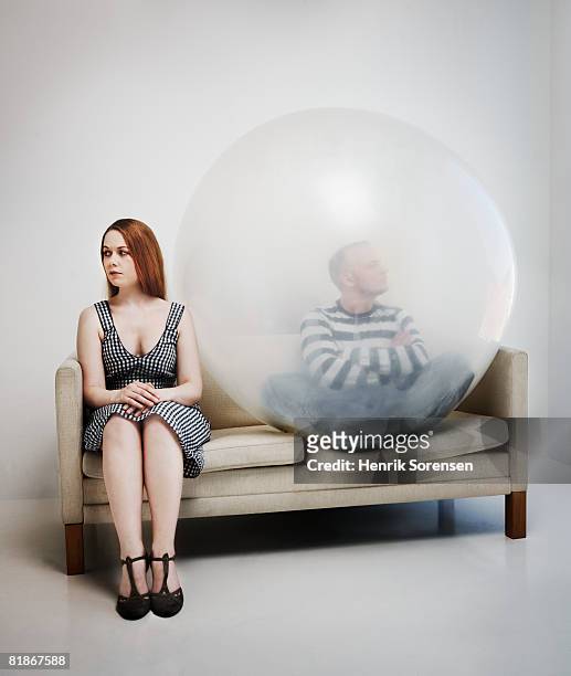 woman sitting in a sofa with a man inside a ballon. - couple trapped stock pictures, royalty-free photos & images