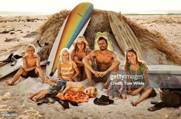 family sitting on the beach with surf boards - wonderlust2015 stock pictures, royalty-free photos & images