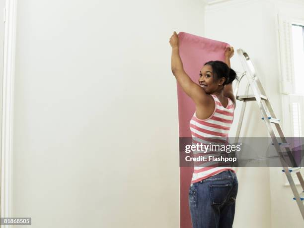 woman hanging wallpaper - hanging wallpaper stock pictures, royalty-free photos & images