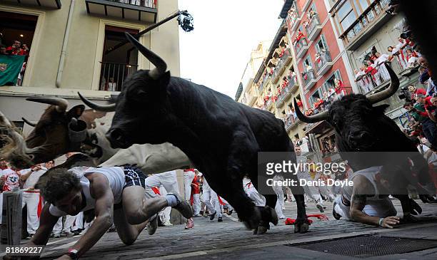 Two runners fall in front of charging fighting bulls at the Mercaderes curve during the third San Fermin running of the bulls on July 9, 2008 in...