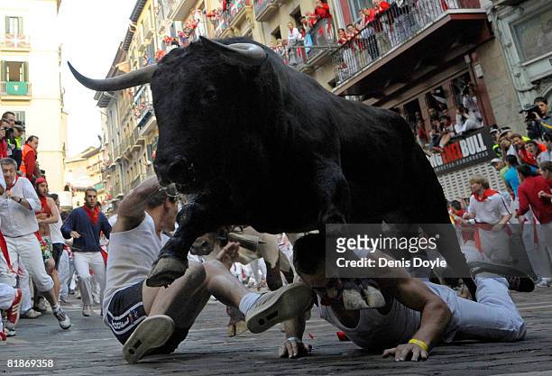 Fighting bull leaps over two fallen runners at the Mercaderes curve during the third San Fermin running of the bulls on July 9, 2008 in Pamplona,...