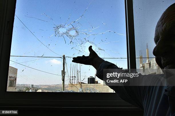 Palestinian man points at a bullet riddelled window pane in the West Bank village of Nilin on July 8 2008, following an Israeli military operation...