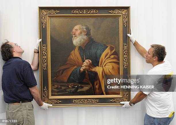 Two mens hang up the picture "Reuiger Petrus" by Dutch painter Gerrit van Honthorst on July 9, 2008 at the Wallraf-Richartz museum in Cologne,...