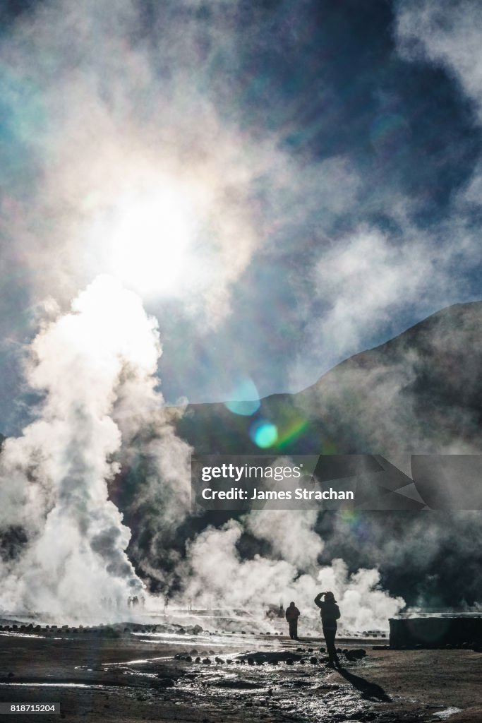 Visitors at dawn watching the sulfur-rich geysers shoot upwards at high altitude (4320m) Geisers de Tatio, near San Pedro de Atacama, Chile