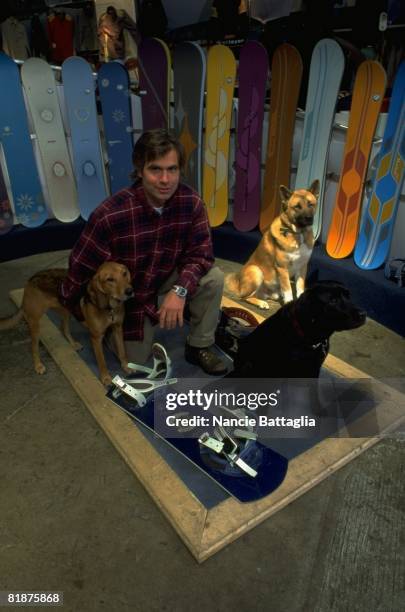 Snowboarding: Portrait of Jake Burton with dogs, animal and snowboard equipment, Burlington, VT