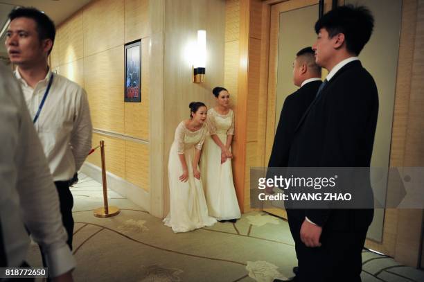 Hostesses stand outside a room where chairman of China's Wanda Group Wang Jianlin, chairman of Sunac China Holdings Limited Sun Hongbin, and chairman...