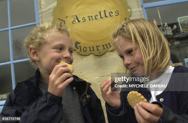 Deux enfants, Camille et Ludovic, goûtent des biscuits d'Antoine Cormier devant sa boutique, le 10 juillet 2001 à Asnelles. Antoine Cormier, ancien...
