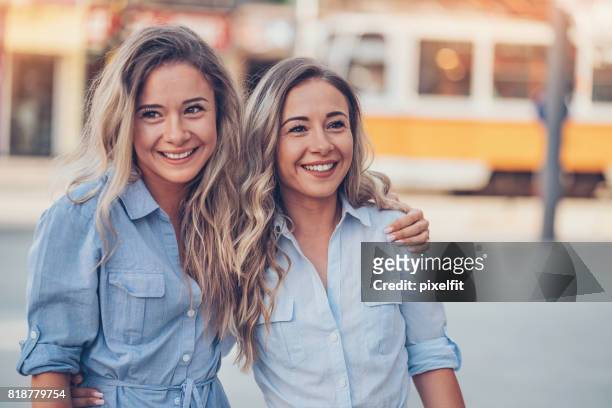 mooie zusters wandelen in de stad - adult twins stockfoto's en -beelden