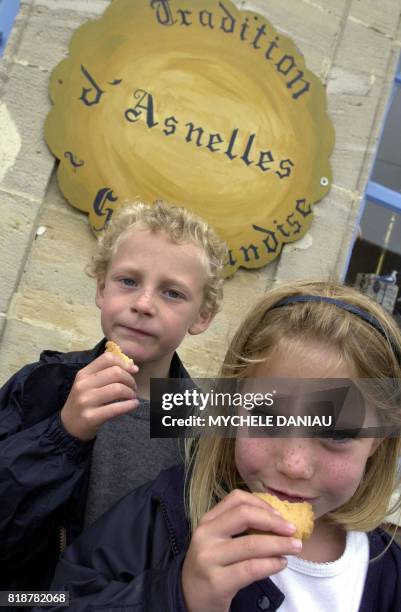 Deux enfants, Camille et Ludovic, goûtent des biscuits d'Antoine Cormier devant sa boutique, le 10 juillet 2001 à Asnelles. Antoine Cormier, ancien...