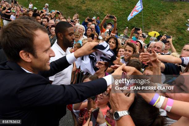 French President Emmanuel Macron shakes hands with people as he arrives in Saint-Martin d'Arc, on July 19, 2017 to meet former cyclists and follow...