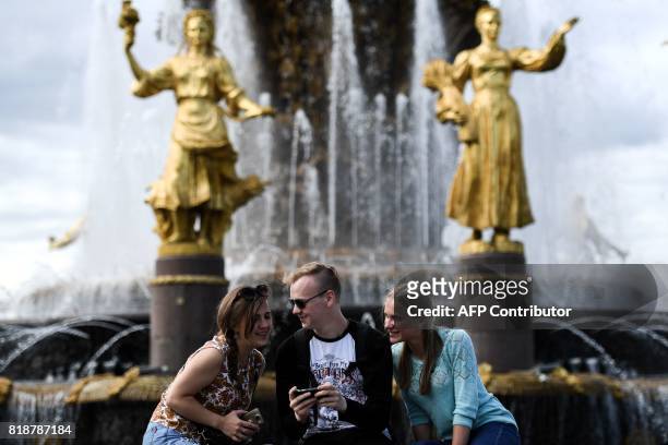 People speak in front of the famous Druzhba Narodov fountain in the All-Russia Exhibition Centre , a trade show and amusement park in Moscow on July...