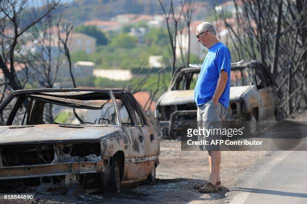This photograph taken on July 19 shows a car owner looking at his burned out vehicle in village of Kucine, near the Adriatic coastal town of Split....