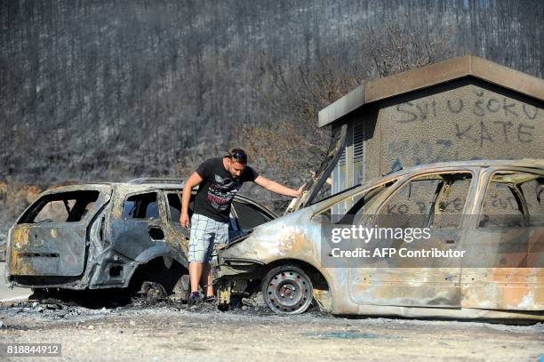 This photograph taken on July 19 shows a car owner looking at his burned out vehicle in village of Kucine, near the Adriatic coastal town of Split....