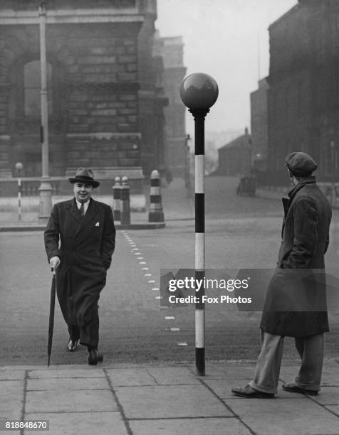 British politician Leslie Hore-Belisha , the Minister of Transport, crossing the road by a new Belisha beacon, circa 1935.